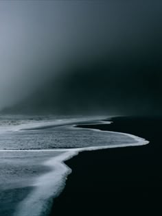 an ocean with waves coming in to shore and dark clouds above the water at night