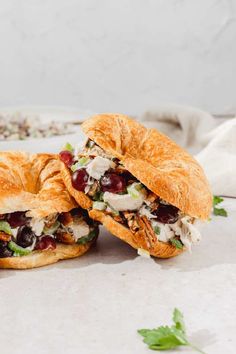 two cranberry chicken salad sandwiches cut in half on a white surface with parsley