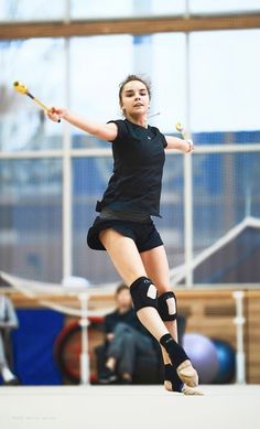 a woman in black shirt and knee pads playing with a tennis racquet on court