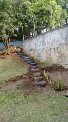 a set of steps made out of tires in the grass next to a concrete wall