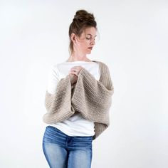 a woman standing with her hands on her hips wearing a knitted sweater and jeans