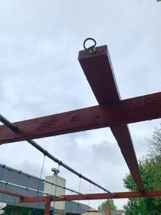 a wooden structure that has some kind of object hanging from it's side, with a building in the background