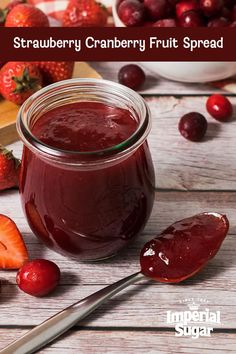 a jar of strawberry cranberry fruit spread with strawberries and cherries in the background