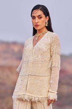 This stunning ivory cord set in georgette features meticulous embroidery and beautiful long tassel detailing on both the palazzo and blouse. White Traditional Sets With Tassels, Traditional White Sets With Tassels, Traditional Anarkali Set With Tassels For Designer Wear, Traditional Tassel Palazzo Set For Wedding, Festive Party Palazzo Set With Tassels, Elegant Off White Palazzo Set With Traditional Drape, Designer Anarkali Set With Traditional Drape And Tassels, Elegant Off White Palazzo Set For Festive Season, Designer Wear Anarkali Set With Tassels