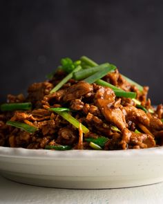 a white bowl filled with meat and green onions