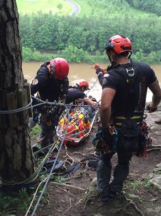 three rescue workers working on the side of a river