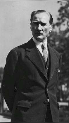 an old black and white photo of a man in a suit with his hands on his hips