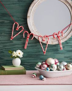 a bowl filled with candy canes sitting on top of a table next to a mirror