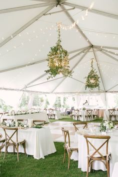 a large tent with tables and chairs set up for an outdoor wedding reception in the grass