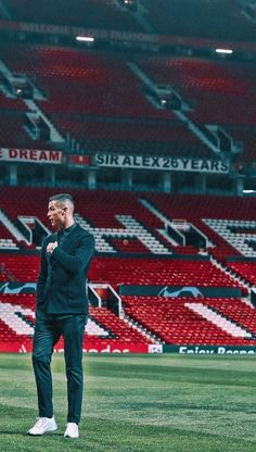 a man standing on top of a soccer field in front of a red bleachers