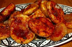 some bananas are sitting on a black and white plate with red glazes over them