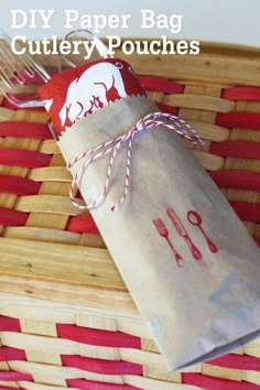 a paper bag sitting on top of a woven basket next to a fork and knife