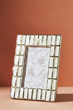 a small mirror sitting on top of a table next to a brown wall with a white frame