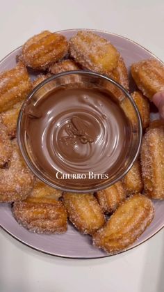 a person dipping chocolate into donuts on a plate