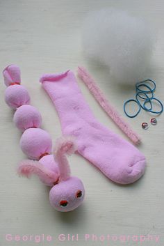 a pink stuffed animal laying on top of a table next to some scissors and yarn