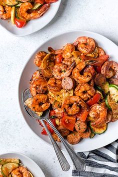 two white plates filled with shrimp and veggies