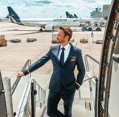 a man in a suit walking down the stairs to an airplane on the tarmac