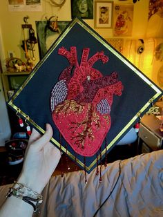 someone holding up a graduation cap with a heart on it