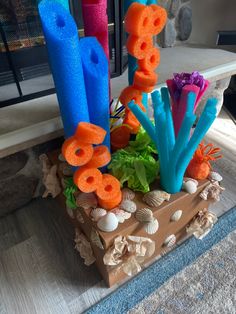 an arrangement of colorful candles and sea shells on a wood block in front of a fireplace