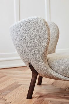 an upholstered chair with wooden legs on a hard wood floor