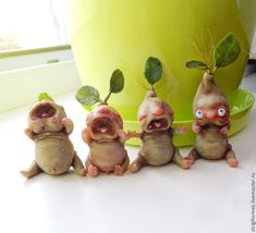 three little figurines with plants growing out of them