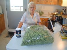 an older woman standing in front of a bag of beans on a kitchen counter top