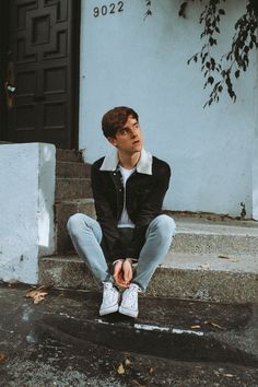 a young man sitting on steps in front of a building