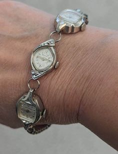 "This bracelet is made from vintage watches dating from the 1930s and up, there are a variety of watches used; this one includes a Bulova with little diamonds on either side and two Caravelle's. The Bulova is a lovely marquis shape marked 10k rolled gold plated. All three watches have pearly white faces with silver hands and numerals. I've recently learned that Bulova only used actual diamonds on their watches! The watches are non-functioning but each is a little piece of beautiful art! Given the age of the components, there will be scratches and scuffs on the watches and crystals. Some may be missing hands or the winding mechanism, but I think that just adds to the vintage look. These bracelets make a statement and are perfect for anyone who loves vintage or steampunk style. Wear one on i Vintage Nickel-free Bracelets For Anniversary, Vintage White Gold Watch With Jubilee Bracelet, Silver Vintage Watch With Bracelet Strap, Vintage Bulova Ladies Watch, Vintage Silver Automatic Watch, Sundance Style, Stretch Band, Watch Bracelet, Stretch Bands