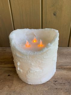 a white candle holder with three lit candles in it