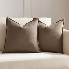 two pillows sitting on top of a white couch