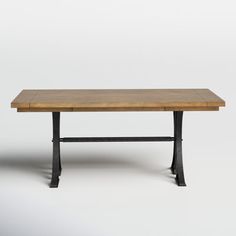 a wooden table sitting on top of a white floor next to a black metal frame