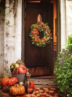 the front door is decorated for fall with pumpkins and other autumn decorating items