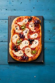 a pizza topped with lots of toppings on top of a wooden table next to a blue wall