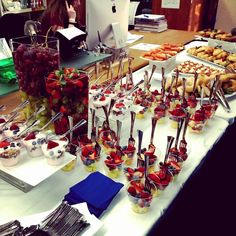 an assortment of desserts on a table with people in the background