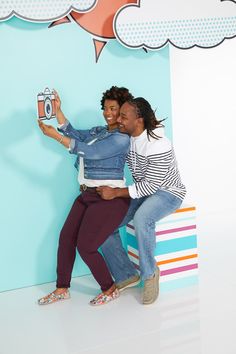 two women taking a selfie in front of a blue wall with clouds and stars