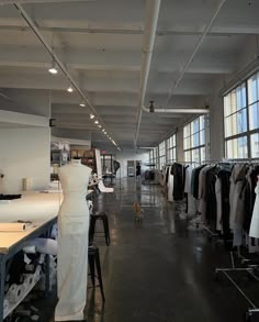 an empty clothing store with lots of clothes on hangers and tables in front of large windows