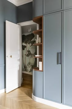 an empty room with blue walls and wooden flooring is pictured in this image, there are bookshelves on either side of the door