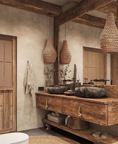 a rustic bathroom with two sinks and baskets hanging from the ceiling over it's sink