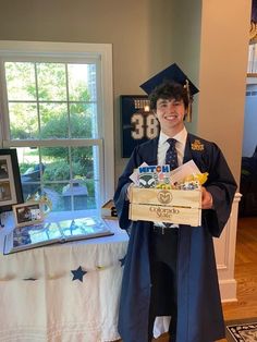 a young man in his graduation gown is holding a box that he made for him