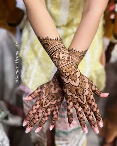 two hands with henna tattoos on them and people in the background looking at each other