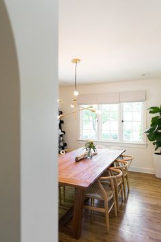 a wooden table sitting in the middle of a living room next to a potted plant