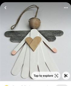 popsicle stick angel ornament with wooden heart on it's back and string attached to the wings