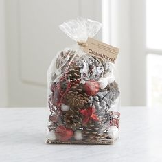 a plastic bag filled with pine cones and other decorations on top of a white counter