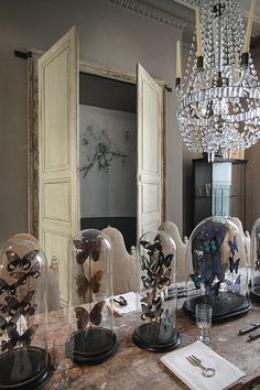 the table is covered with glass cloches and other decorative items in front of an open door