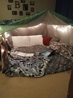 an unmade bed in a room with lights on the walls and sheets all over it