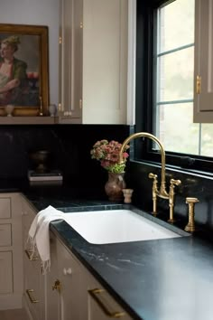 a kitchen with black counter tops and gold faucets on the sink's side