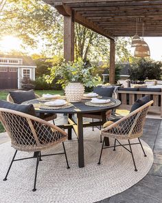 an outdoor dining area with wicker chairs and round table set up on a patio