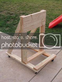 a small wooden chair sitting on top of a cement floor next to a red slide