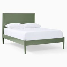 a bed with white sheets and green headboard