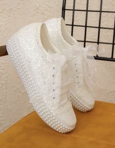 a pair of white shoes sitting on top of a wooden table next to a wall